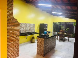 a kitchen with a yellow wall and a counter at Aconchego da Serra ibiapaba in Ipu