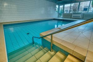 ein großer Pool mit einer Treppe in einem Gebäude in der Unterkunft Aussicht auf Natur, Pool, Grill, Kino, Sauna in Schönwald