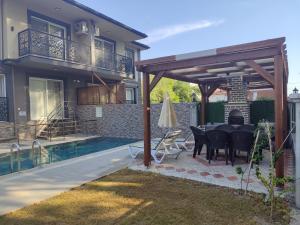a patio with a table and a fireplace next to a house at Villa BB Mugla 1 in Ortaca