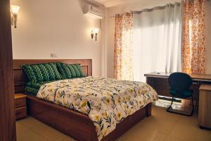 a bedroom with a bed and a desk and a window at SERENITY Flat3 in Pointe-Noire