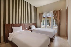 a bedroom with two beds and a window at Askara Canggu Townhouse in Canggu