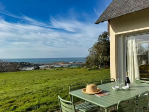 une table verte avec un chapeau assise sur une terrasse couverte dans l'établissement Ker Wind - panoramic sea view house Primel 8-10p, à Plougasnou