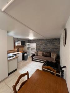 a kitchen and a living room with a couch and a table at Appartement en rez de jardin in La Roche-de-Rame