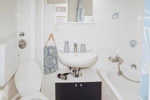 a white bathroom with a sink and a toilet at Sunny Maritime Apartment near Hannover central station in Hannover