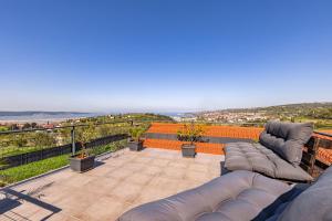 a patio with couches and chairs on a balcony at LaraBella Salt fields view studio in Portorož