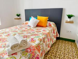 a bedroom with a bed with colorful sheets and pillows at Apartamento centro 1A in Huelva