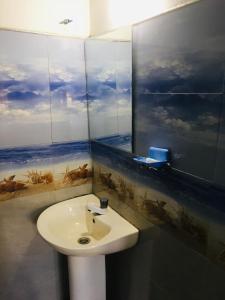 ein Badezimmer mit einem Waschbecken und einem Wandgemälde in der Unterkunft Sams Cottage in Nuwara Eliya