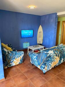 a living room with two couches and a surfboard on the wall at Blue Wave House Corralejo in La Oliva