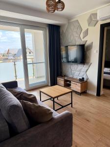a living room with a couch and a flat screen tv at Ogrodowa70 Apartment in Sztutowo
