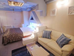 um quarto de hotel com um sofá e uma cama em Hotel Plage (Adult Only) em Yokohama