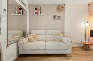 a living room with a white couch and a mirror at Studio La perle clim balcon parking privé in Cap d'Agde
