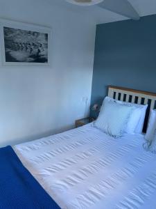 ein Schlafzimmer mit einem weißen Bett mit blauen Wänden in der Unterkunft Pond Cottage in Coverack