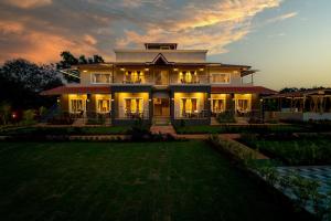 a large house with its lights on at dusk at The Green Bliss Nature's Resort Nagaon in Nagaon