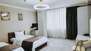 a hotel room with two beds and a chandelier at Taj Mahal Osh in Osh