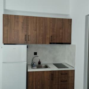 a kitchen with wooden cabinets and a sink at Thanos ,Rooms and Apartments in Ouranoupoli