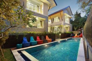 a swimming pool with colorful pillows next to a house at Askara Canggu Townhouse in Canggu