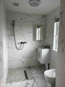 a white bathroom with a shower and a sink at River View - Modern 4 Bedroom Bungalow in Cabraghkeel +15 photos