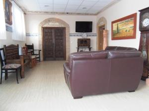 a living room with a leather couch and a tv at Domus Viatoris in Sahagún