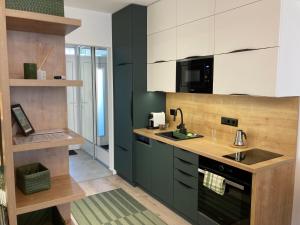 a kitchen with green and white cabinets and a sink at Gold & Green Apartment in Keszthely