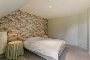 a bedroom with a bed and a brick wall at La Délice in Érezée