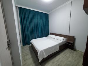 a bedroom with a bed and a blue curtain at Квартира в Батуми in Batumi