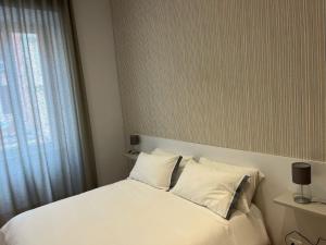 a bedroom with a bed with white sheets and a window at L'Aurora Casa Vacanze in Anzio
