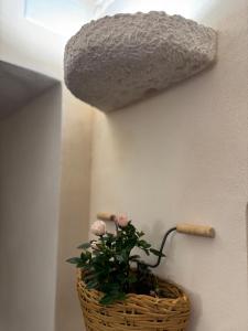 un cesto con fiori rosa accanto a un muro di Volta Meraviglia a Martina Franca
