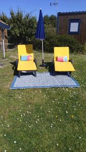 two yellow chairs with pillows sitting next to an umbrella at Mobilhome Metanova in Camiers +9 photos