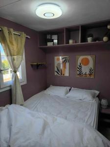 a bedroom with a white bed and a window at Mobilhome Metanova in Camiers