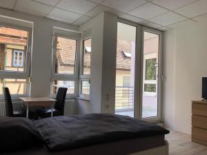 a bedroom with a bed and a table and windows at Neu saniert, 7 Personen, direkt an der Autobahn und Mercedes Werk in Sindelfingen