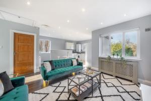 a living room with a green couch and a table at Luxury Tottenham Stadium Retreat - 2 minute walk to stadium in London