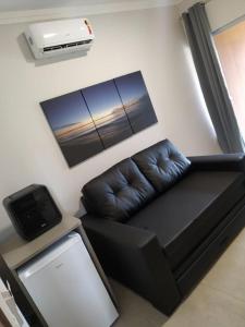 a black leather couch in a living room with a air conditioner at Grandes Lagos Thermas Resorts in Santa Clara dʼOeste +4 photos