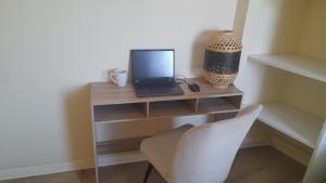 a desk with a laptop and a chair in a room at Cosy T3 Oiseau de Paradis Billard Balnéothérapie proche aéroport et centre-ville in Saint-Denis