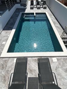 una piscina con due sedie in un edificio di Luna Deluxe a Novalja (Novaglia)