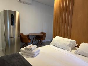 a bedroom with a bed with towels and a refrigerator at Flat ao lado da Praia - Rifaina in Rifaina