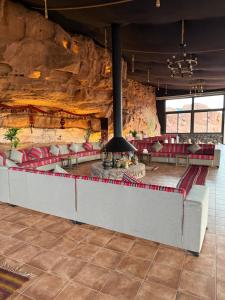 a room with red chairs and a stone wall at Wadi Rum Bedouin Camp in Wadi Rum