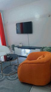 a living room with an orange chair and a table at Tsavo in Ongata Rongai 