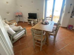 a living room with a wooden table and chairs at L' Atelier, Marpissa Paros in Márpissa