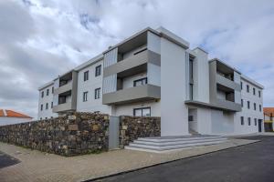 un edificio de apartamentos blanco con una pared de piedra en Nono Guest House, en Ribeira Grande