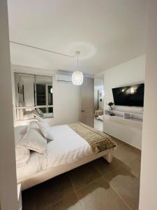 une chambre blanche avec un lit et une télévision à écran plat dans l'établissement Apartamento Descanso Cartagena, à Manzanillo del Mar 19 autres photos