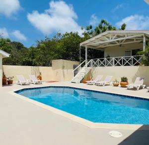 een zwembad met stoelen en een huis bij Mini Resort Kaya Verdi in Willemstad