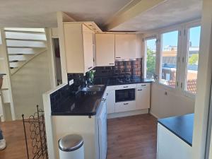a kitchen with white cabinets and a black counter top at Juul's Rooftop gratis parkeren in Noordwijk