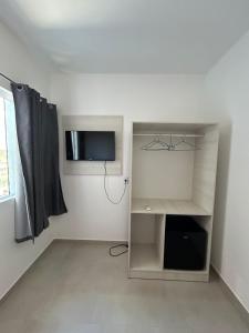 a white room with a tv and a shelf at Pousada casa da amizade in Penha