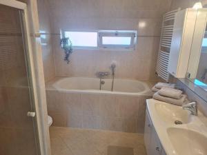 a bathroom with a tub and a sink at Have a nice stay! - Juul's Rooftop, free parking in Noordwijk