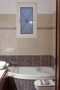 a bathroom with a tub and a toilet and a window at Villa Afandou Bliss in Afantou +29 photos