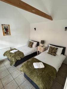 a room with two beds and a table with a lamp at The Old Stables in Mews in Kessingland