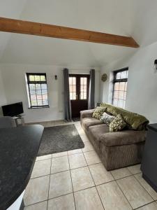 a living room with a couch and two windows at The Old Stables in Mews in Kessingland