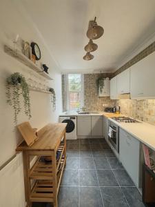 a kitchen with white cabinets and a wooden table at Verulam Palms - Private Garden & Parking in Bournemouth