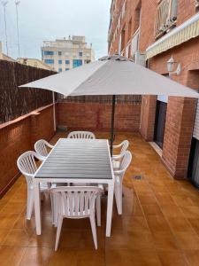 a white table and chairs with an umbrella on a balcony at Vacaciones en la playa in Sant Carles de la Ràpita