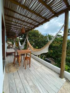 a porch with a hammock and a table and chairs at Chalé Green Vila Mathilde in Icapuí